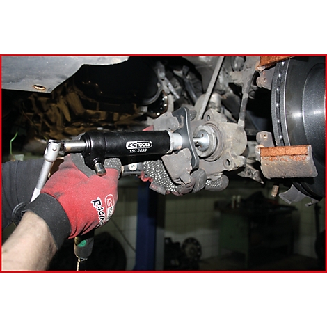 Person repariert Bremse mit Werkzeug, roter Handschuh, KS Tools. Das Bild zeigt Detail des Reparaturvorgangs.